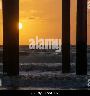 Lever du soleil au Claremont Pier avec des vagues se brisant sur la super-structure, Lowestoft Banque D'Images