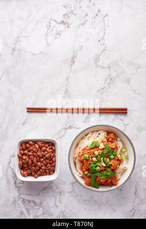 Nouilles shan avec arachides et baguettes à table en marbre blanc. La cuisine birmane myanmar plat traditionnel. la nourriture. les nouilles de riz avec du porc dans les tomates Banque D'Images