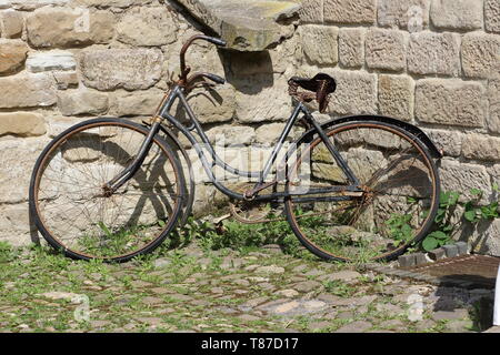 Vieux vélo rouillé garé contre un mur Banque D'Images