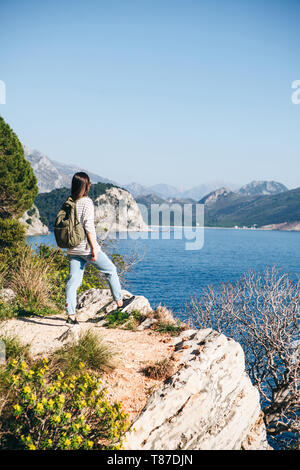 Un touriste avec un sac à dos en haut d'une falaise ou une colline à côté de la mer ressemble dans la distance. Voyager seul. Banque D'Images