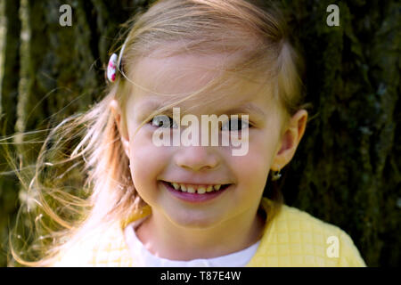 Portrait de petite fille debout et le tronc de l'arbre ancien Banque D'Images