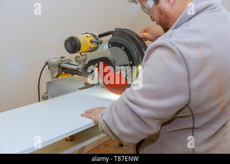 L'homme aide charpentier electro vu laminé coupe circulaire étagères blanches Banque D'Images