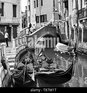 Venise, Italie - le 18 juin 2018 : Deux gondoles sur canal près de petit pont dans l'attente des touristes. Image en noir et blanc Banque D'Images