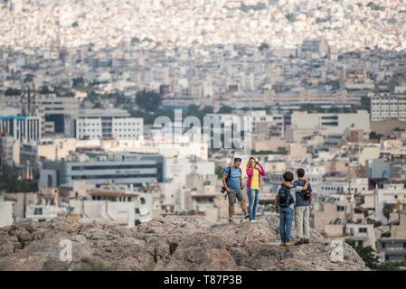 Les touristes de la colline de l'Acropole surplombant la ville d'Athènes Grèce / ATHÈNES, Grèce - les touristes se tiennent sur la colline de l'Acropole, en prenant dans une large vue sur le paysage urbain tentaculaire d'Athènes ci-dessous. La colline est le site de l'ancienne Acropole, un site classé au patrimoine mondial de l'UNESCO dont les structures classiques - y compris le Parthénon, l'Érechthéion et le temple d'Athéna Nike - datent principalement du Ve siècle av. J.-C. Le point de vue élevé offre l'un des panoramas les plus complets de la capitale grecque et de sa région Attique environnante. Banque D'Images