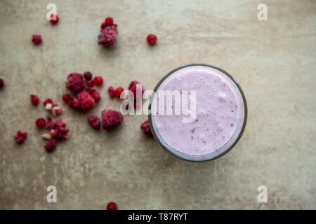 Mise en page créative faite de framboise, de fraise et de noix de coco smoothie. Concept alimentaire. Sur le Smoothie fond gris. Banque D'Images