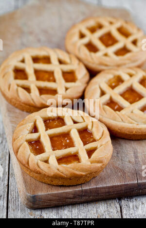 Tartes fraîchement cuit au four avec de la marmelade ou confiture d'abricot sur remplissage sur la planche à découper sur fond de table en bois rustique. Banque D'Images