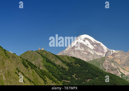 Tsminda Sameba l'église géorgienne située sur la colline verte au-dessus de la ville Stepantsminda. En arrière-plan Pointe Milou Kazbeg. Banque D'Images