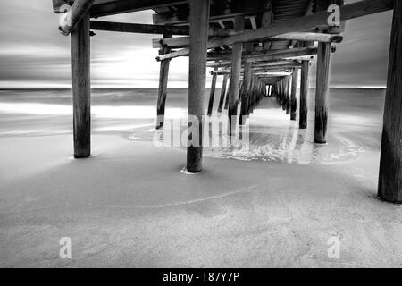 Comme le soleil se lève derrière la jetée de pêche Sandbridge, les vagues crash sous-thèmes : - Point de vue, la paix, la longue exposition, obturation lente, Misty Banque D'Images