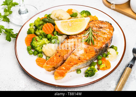 Pavé de saumon grillé avec des légumes sur blanc. Banque D'Images