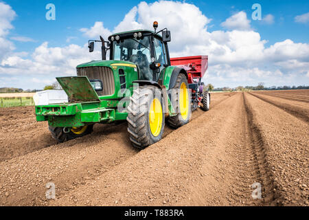 La plantation mécanisée de pommes de terre de semence à l'aide d'un semoir 3 rangs dewulf belt derrière un tracteur John Deere. Banque D'Images