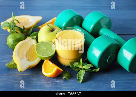 Verre de smoothie savoureux avec des ingrédients et des haltères courtes sur table en bois. Concept de régime Banque D'Images