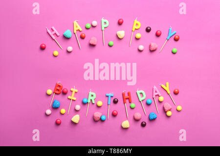 Mots JOYEUX ANNIVERSAIRE faites des bougies et des bonbons sur un fond de couleur Banque D'Images