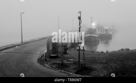 Une soirée en rouleaux de brouillard de la mer de l'Atlantique et des couvertures Hout Bay Harbour dans la brume sur la péninsule du Cap, près de Cape Town, en Afrique du Sud Banque D'Images