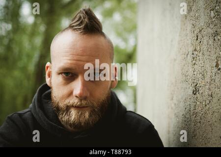 De graves ou calme jeune homme barbu assis devant l'appareil photo Banque D'Images