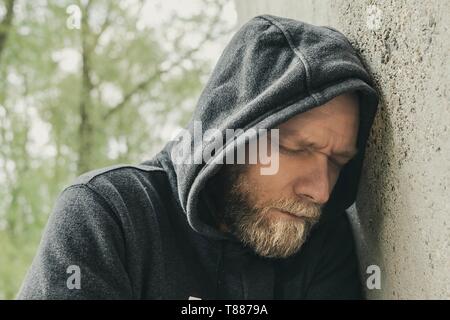 Homme triste posant sa tête contre un mur Banque D'Images