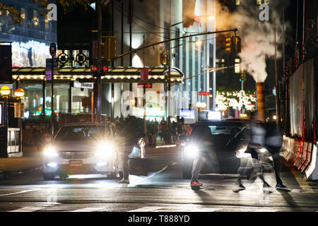 La vie quotidienne dans les rues de Manhattan, avec troubles de personnes traversant une route très fréquentée à l'intersection de la nuit, New York, USA. Banque D'Images