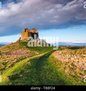 Regarder en arrière vers l'Île Sainte château sur un lever du soleil d'hiver & storm clouds rolling in & chemin menant à Castle Banque D'Images