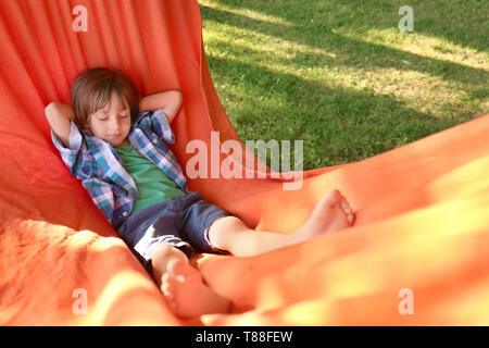 Cute little boy relaxing in hammock on journée ensoleillée à l'extérieur Banque D'Images