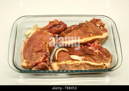 De grands morceaux de filet de porc mariné et saupoudré d'épices dans une verrerie pour barbecue Banque D'Images