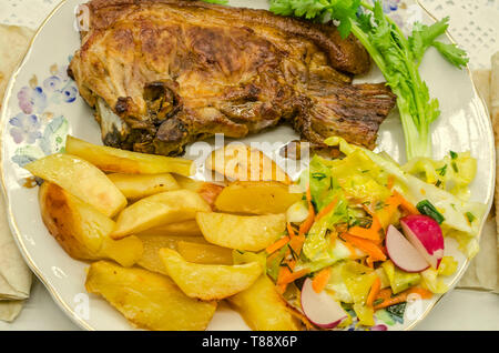 Salade de chou cru haché, les carottes et les morceaux de radis près d'un morceau de porc frit et frites de pommes de terre avec un brin de coriandre, sur une assiette de porcelaine Banque D'Images
