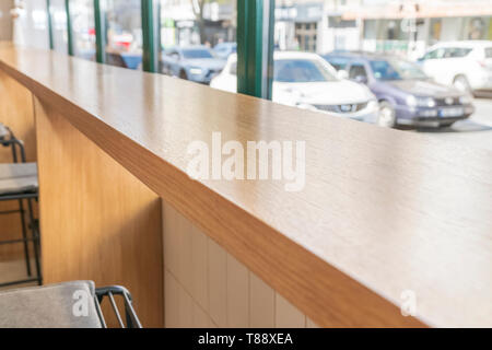 Table en bois dans un café par la fenêtre donnant sur la rue avec des voitures qui passent Banque D'Images