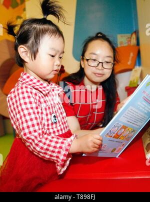 Beijing, Chine. 12 mai, 2019. Une fille lit un livre avec sa mère à Beijing, capitale de la Chine, le 12 mai 2019. Un centre d'éducation de la petite enfance a organisé un événement de lecture livre d'images pour promouvoir la lecture parent-enfant à Beijing. Credit : Liu Lianfen/Xinhua/Alamy Live News Banque D'Images