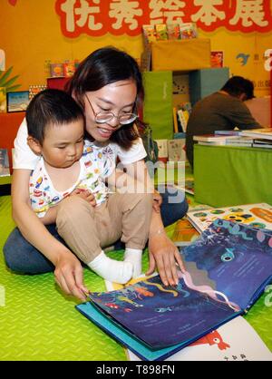 Beijing, Chine. 12 mai, 2019. Un garçon lit un livre avec sa mère à Beijing, capitale de Chine, le 12 mai 2019. Un centre d'éducation de la petite enfance a organisé un événement de lecture livre d'images pour promouvoir la lecture parent-enfant à Beijing. Credit : Liu Lianfen/Xinhua/Alamy Live News Banque D'Images