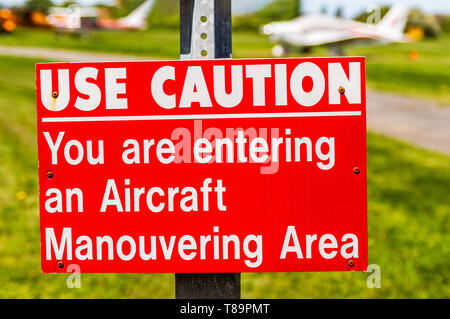 Startseite avion rouge et blanc, attention pendu sur poste à d'atterrissage. Banque D'Images