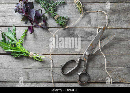 Bouquets de fines herbes avec des ciseaux et corde sur fond de bois Banque D'Images