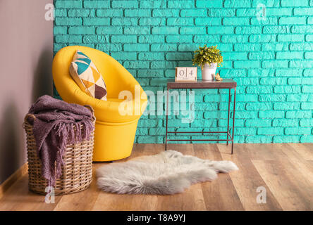 L'intérieur de cette chambre moderne avec panier, fauteuil et plante sur la table près de mur de couleur Banque D'Images