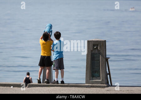 Seattle, Washington : deux garçons-nous une lunette pour voir les bateaux passer le long de Alki Beach à West Seattle comme la ville est confrontée à nombre record de chaleur pour la deuxième journée consécutive. Banque D'Images