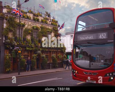 Le Churchill Arms pub - connu sous le nom de la pub plus colorés à Londres et un bus à impériale rouge arrête dans la rue. Banque D'Images