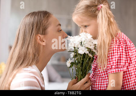 Jolie petite fille et sa mère à la maison fleurs renifleurs Banque D'Images