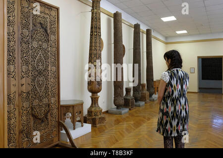 Un visiteur regardant une ancienne porte en bois richement sculpté exposée au Musée des Arts appliqués situé dans l'ancienne maison du diplomate russe impérial Alexandre Polovtsev dans la ville de Tachkent capitale de l'Ouzbékistan Banque D'Images