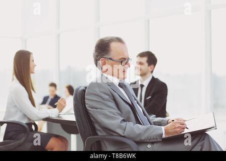 Portrait of a smiling man in suit avec son équipe travailler derrière Banque D'Images