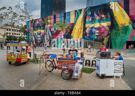 Le Brésil, l'état de Rio de Janeiro, Rio de Janeiro, ville classée Patrimoine Mondial de l'UNESCO, centre, quartier des Docks, Utopia station de tramway Aquario, mur toile de l'artiste Eduardo Kobra peint en 2016 pour les Jeux Olympiques sur 3000 m², vendeurs de rue Banque D'Images