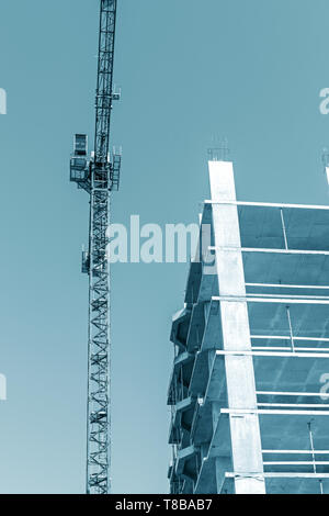 Grue à tour de haut standing près de l'îlot de l'édifice en construction contre fond de ciel bleu Banque D'Images