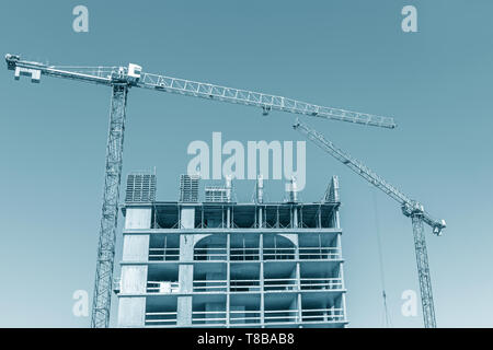 Immeuble de grande hauteur en construction. site de construction avec des grues contre le ciel bleu Banque D'Images