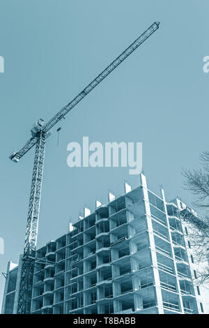 Grue a tour près de l'immeuble en construction contre blue sky background. Vue de dessous Banque D'Images