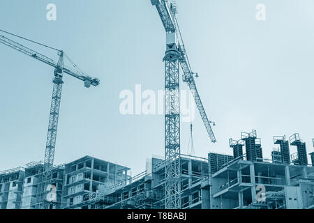 Ville moderne bâtiment en construction et grues à tour against blue sky background. Vue de dessous Banque D'Images