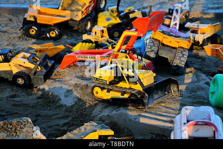 Plusieurs camions de jouets laissés dans une carrière de sable à la fin de la journée Banque D'Images