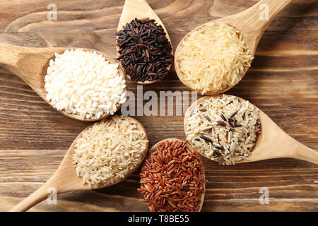 Différents types de riz dans les cuillères sur fond de bois Banque D'Images