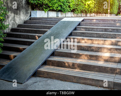 Plank extérieur d'escaliers en bois en bois avec rampe pour fauteuil roulant sur l'arbre vert l'arrière-plan. Escalier en bois ancien en bois avec chemin de pente dans le jardin. Banque D'Images