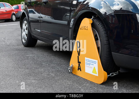 Une voiture sur une rue de banlieue au Royaume-Uni avec une pince munie d'roue DVLA jaune Banque D'Images