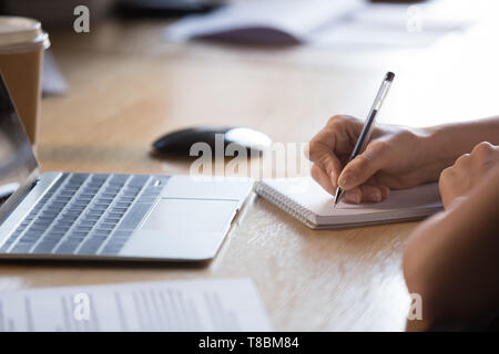 Close up female hands holding pen écrit dans le bloc-notes Banque D'Images