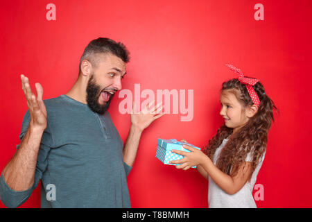 Little girl giving present à son père sur un fond de couleur Banque D'Images