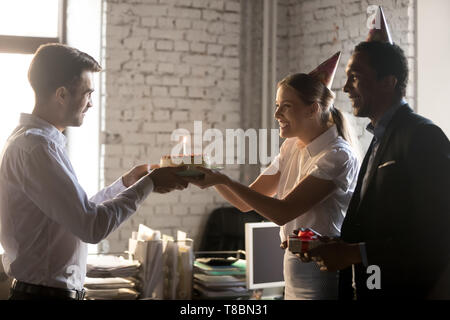 Compagnon de travail avec divers collègues féliciter anniversaire donnant cake with candle Banque D'Images