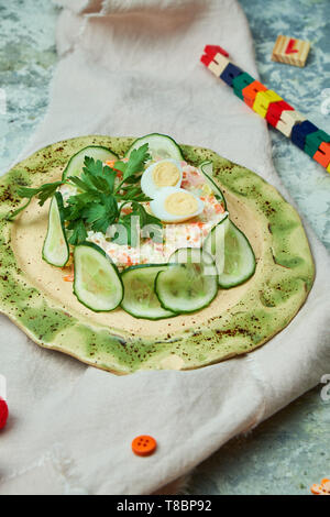 Salade de crabe et de tranches de concombre sur un beau plat fond gris Banque D'Images