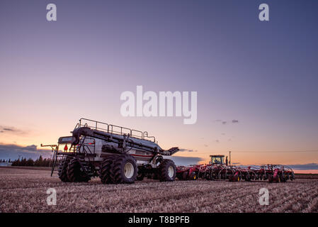 Swift Current, SK/Canada - Mai 10, 2019 : Coucher de soleil sur tracteur Caterpillar et Bourgault du matériel d'ensemencement dans le domaine de la Saskatchewan, Canada Banque D'Images