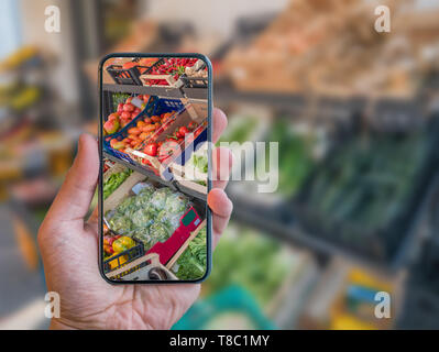 L'épicerie de réalité augmentée mobile app. La main est maintenant portable avec la numérisation de l'application AR des légumes au marché alimentaire. Banque D'Images